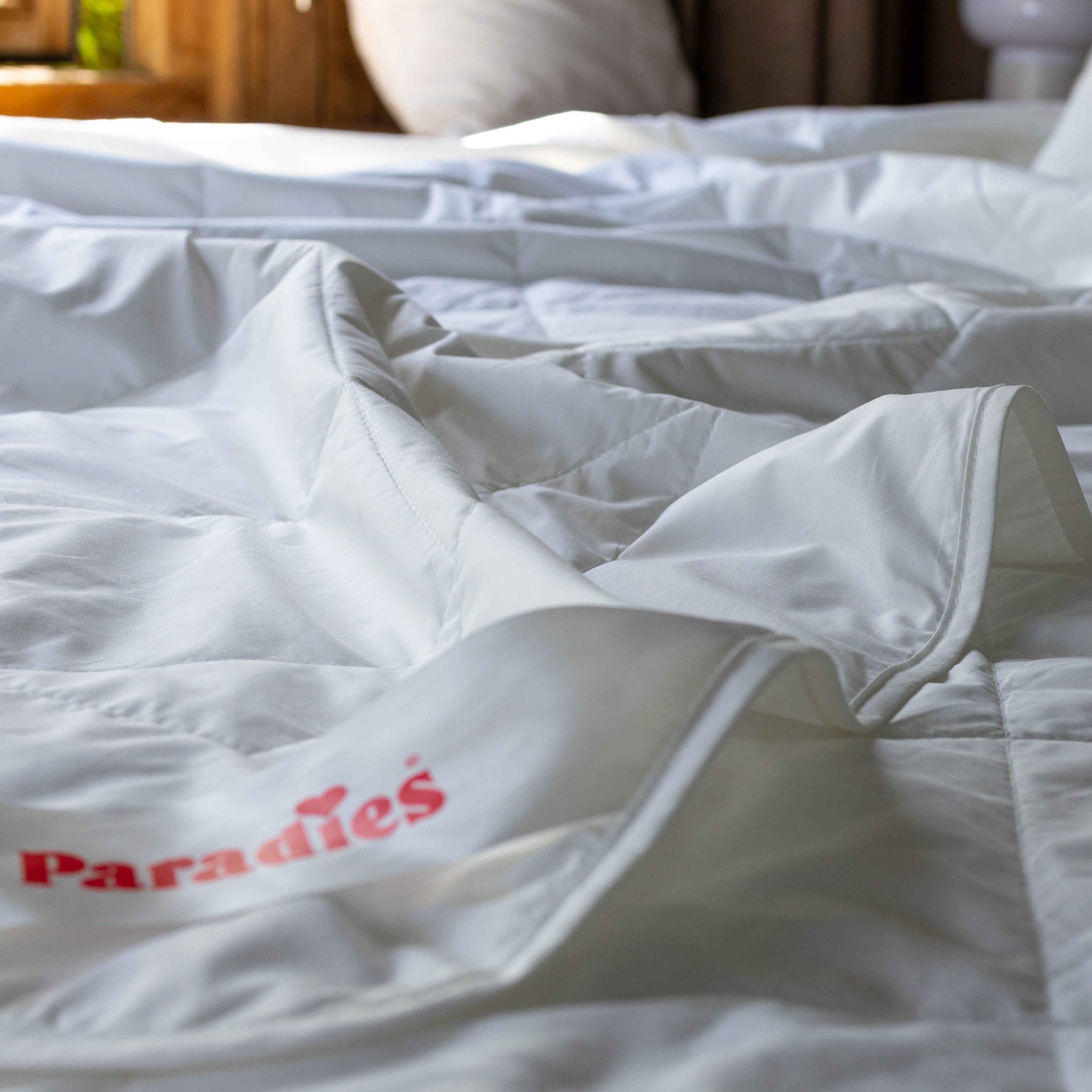 Nahaufnahme der extra dünnen Sommerdecke Cool Dream Bio auf einem Bett mit rotem Paradies-Logo auf dem Etikett